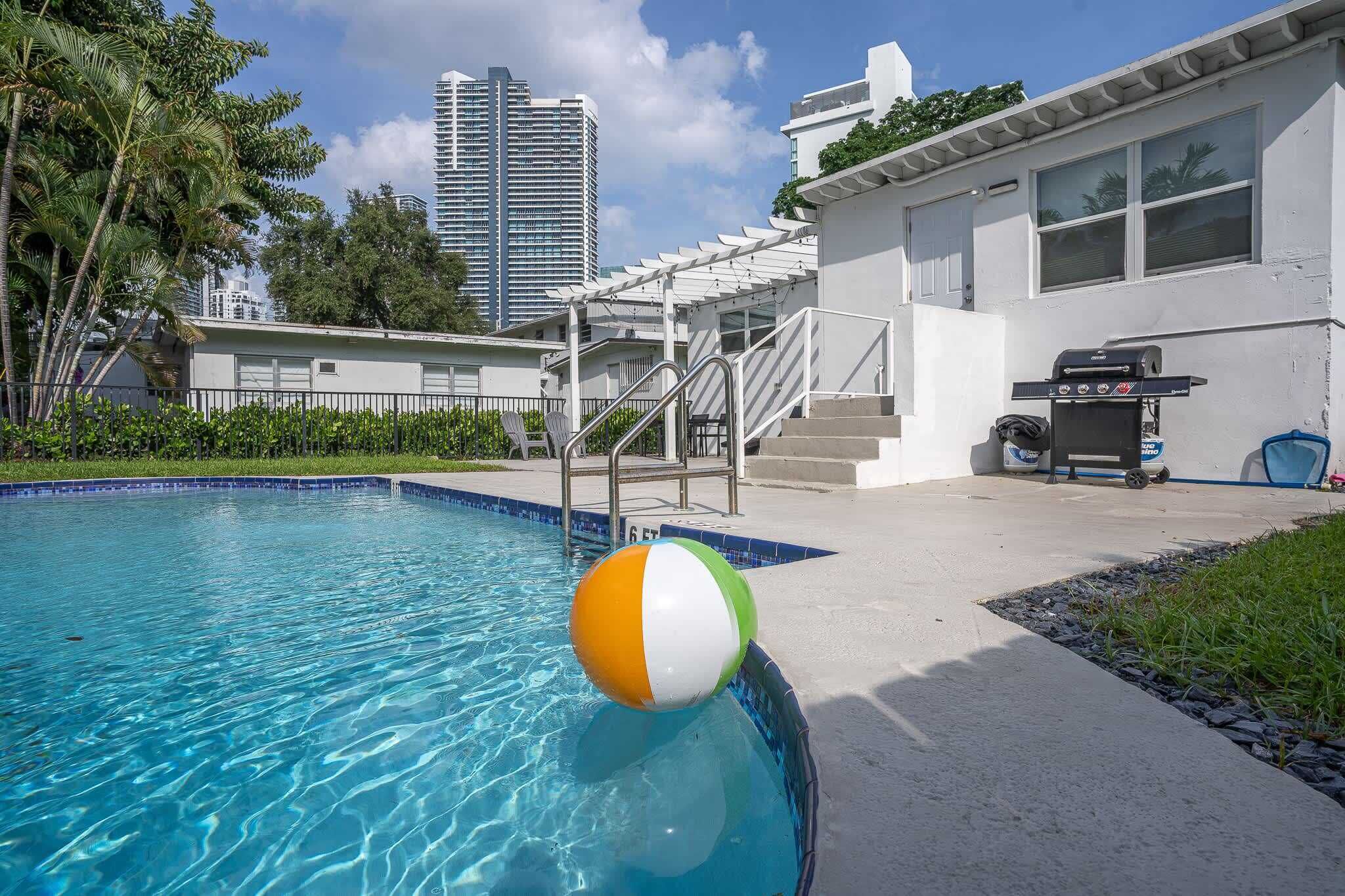 Una piscina con un pallone da spiaggia, un barbecue e una scalinata che conduce a un'area coperta.