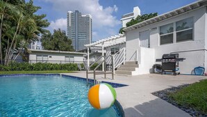 Una piscina con un pallone da spiaggia, un barbecue e una scalinata che conduce a un'area coperta.