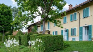 A two-story house with a stone pathway leading to the entrance, surrounded by well-maintained hedges and flowering plants. - La Rocchetta 1915 by Interhome (Cortazzone)