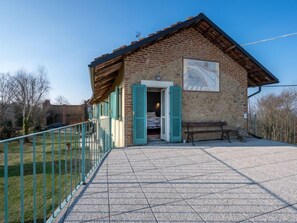Ein kleines Backsteinhaus mit einer gefliesten Terrasse, einer Bank und einem Zaun.