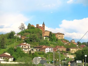 Eine Stadt auf einem Hügel mit einer historischen Burg, umgeben von Wohnhäusern und üppigem Grün.