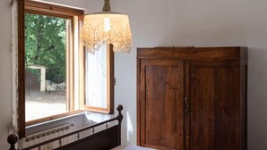 A bedroom with a wooden bed frame, a window with a lace curtain, and a wooden wardrobe. - Villa Le Pine by Interhome (Anghiari)