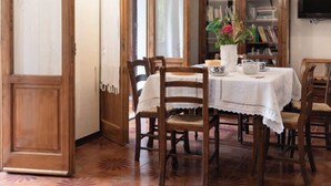 A dining area with a wooden table, chairs, and a cabinet with books. - Villa Le Pine by Interhome (Anghiari)