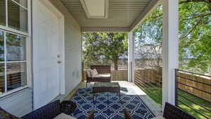 A covered porch with a patterned floor, wicker furniture, and a view of the backyard. - 7South home across street from Lake Hamilton (Hot Springs)