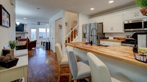 A modern kitchen with white cabinets, a wooden countertop, and stainless steel appliances. - 7South home across street from Lake Hamilton (Hot Springs)