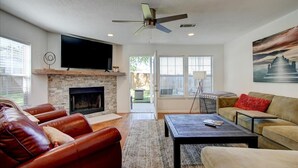 A modern living room with leather sofas, a fireplace, a flat-screen TV, and a large painting. - 7South home across street from Lake Hamilton (Hot Springs)