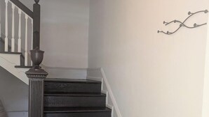Eine Treppe mit dunklen Holzstufen und einem weißen Geländer, die zu einer oberen Etage führt.