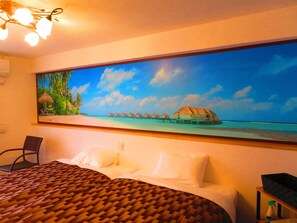 A hotel room with a bed, a chair, a painting of a beach scene, and a ceiling light fixture. - aohotel (Nago)