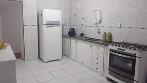 Una cocina con gabinetes blancos, un refrigerador, una estufa y un microondas.