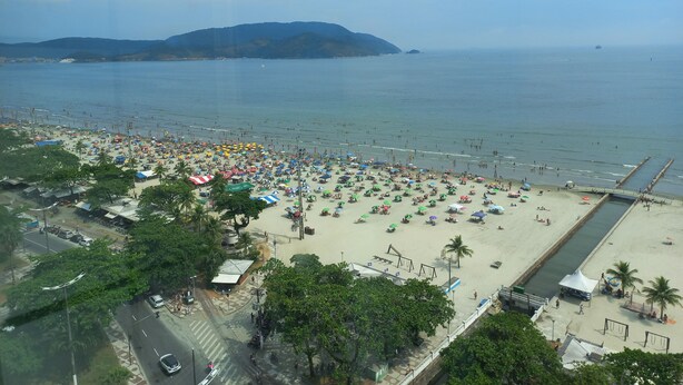 Una playa con muchas sombrillas y gente.