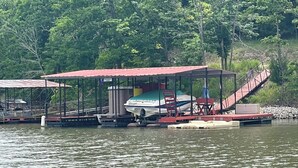 Eine Anlegestelle mit überdachter Sitzgelegenheit, einem Boot und einer Treppe, die zu einer Plattform führt.
