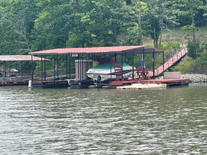 A dock with a covered seating area, a boat, and a staircase leading to a platform.