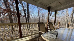 Ein überdachter Außenbereich mit Tisch und Stühlen, umgeben von einer Holzterrasse und einem Geländer aus Seil.