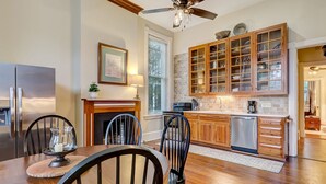 A modern kitchen with wooden cabinets, a built-in oven, and a dining area with a wooden table and chairs. - On Lafayette Square, Heated Pool Access (Savannah)