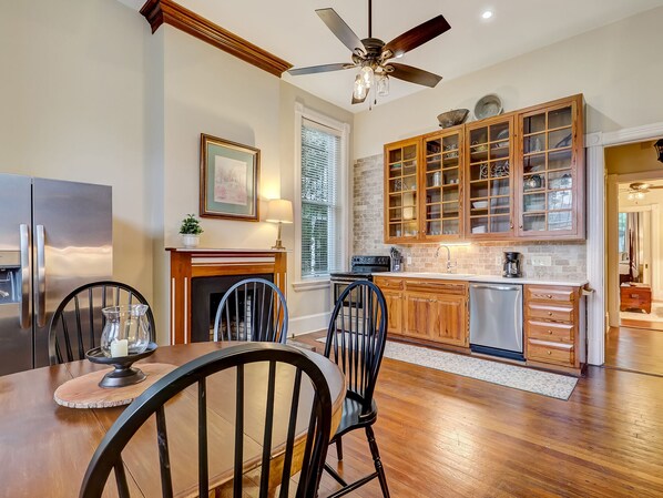 A modern kitchen with wooden cabinets, a built-in oven, and a dining area with a wooden table and chairs. - On Lafayette Square, Heated Pool Access (Savannah)
