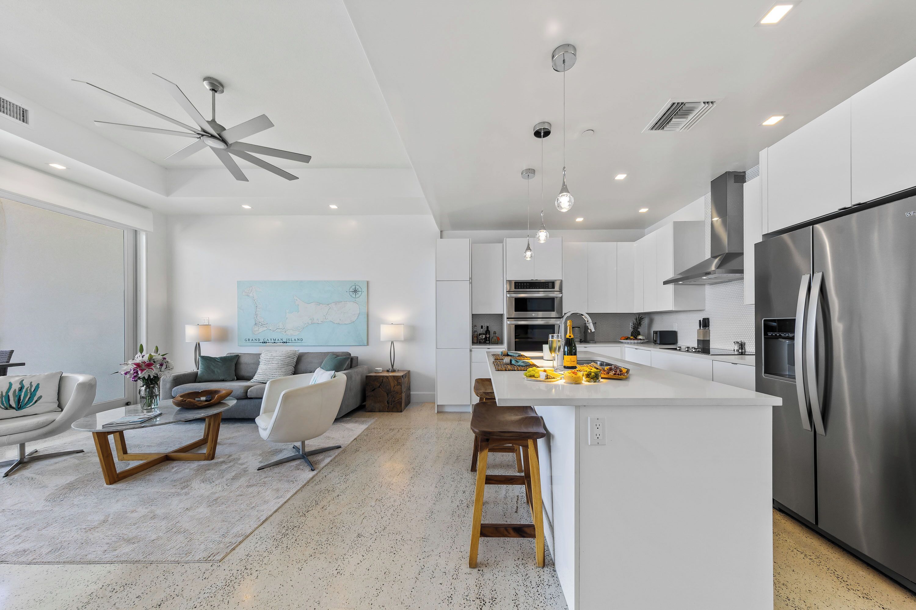 A modern kitchen with a central island, stainless steel appliances, and a ceiling fan.