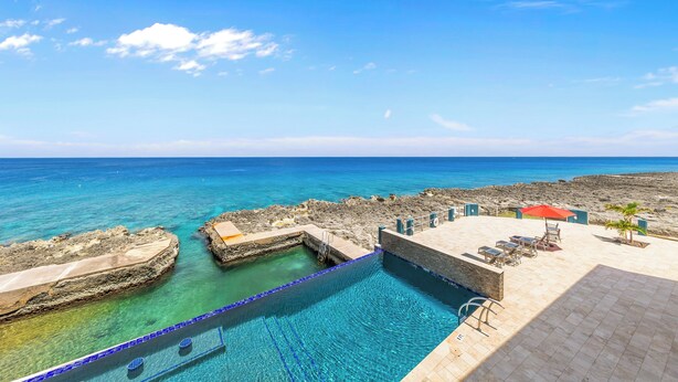 Una piscina con agua azul cristalina, una orilla rocosa y vistas al mar.