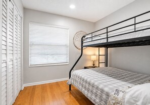 A room with a bunk bed, a window with blinds, a bedside table with a lamp, and a wall clock. - 3697 Orlando Vacational Apartment 1st floor near Universal Studios (Orlando)
