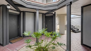 Un edificio moderno con un patio central que presenta una planta, una escalera y una puerta marcada con el número 107.