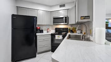 Cozinha moderna equipada com frigorífico, micro-ondas, fogão e pia.