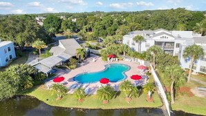 Un resort con piscina, palmeras y vistas del entorno.