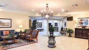 Un salón espacioso con candelabro, asientos cómodos y un ventanal grande.