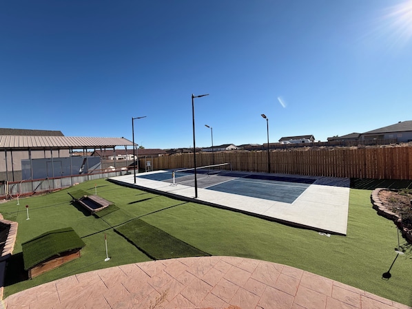 A residential outdoor area with a swimming pool, artificial grass, and a wooden fence.