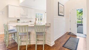 A kitchen with white cabinets, a marble countertop, and a dining area with green chairs. - Pet Friendly Long-Term Rental - 25 Day Min  - Fenced Backyard - Grill (St. James)