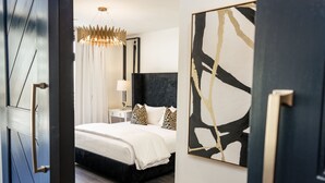 Un dormitorio moderno con una cama grande, una mesita de noche, una lámpara y una obra de arte en la pared.