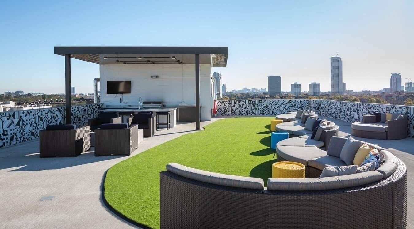 Eine Dachterrasse mit integriertem Grill und Sitzgelegenheit, mit Blick auf die Skyline der Stadt.