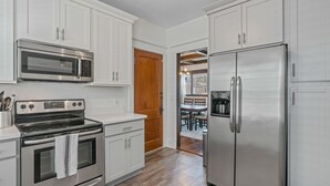 Une cuisine moderne dotée d’appareils électroménagers en acier inoxydable, de meubles blancs et d’une porte en bois.