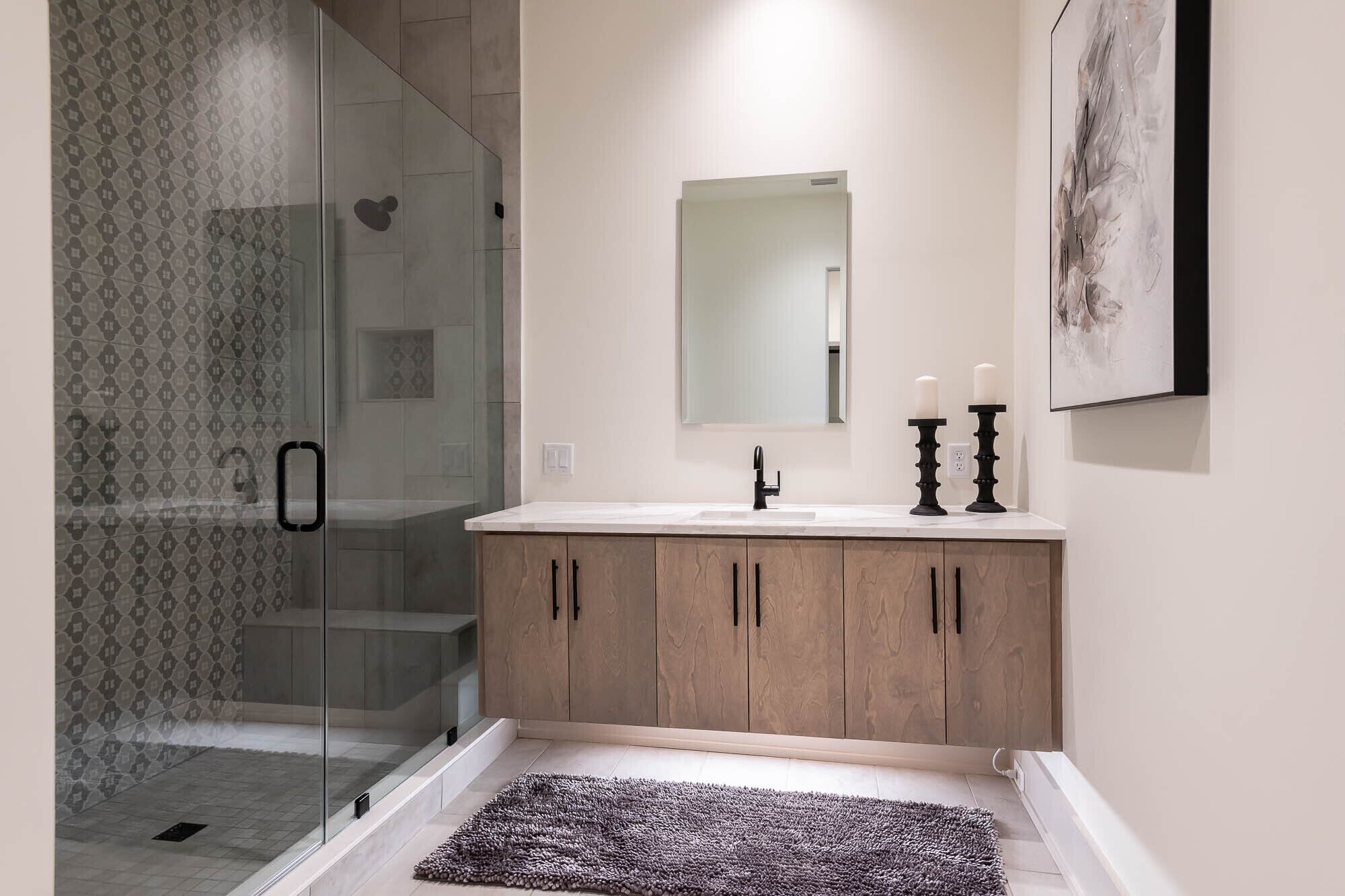Ein modernes Badezimmer mit Duschkabine aus Glas, Waschbecken mit Spiegel und Holzschrank.