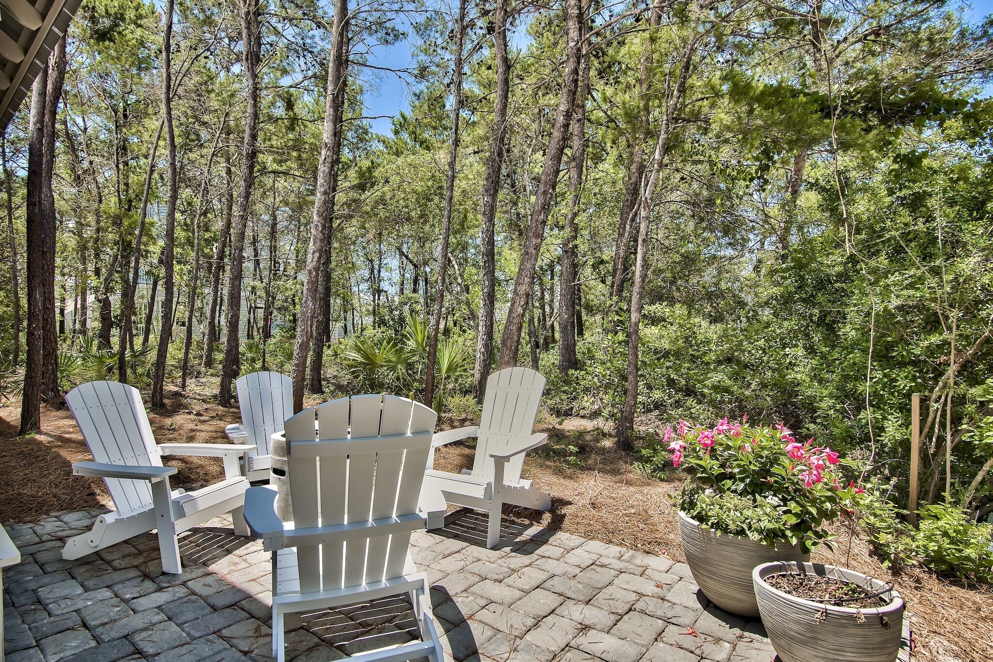 A patio area with Adirondack chairs and potted plants.