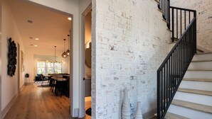 Un intérieur moderne avec un escalier, des murs en briques blanches et un coin repas baigné de lumière naturelle.