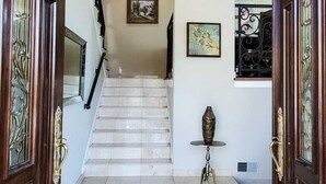 Une entrée somptueuse, ornée d’un lustre, d’un escalier et d’un vase posé sur une petite table.