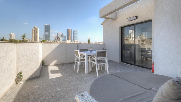 Eine Dachterrasse mit Tisch und Stühlen, einer Sitzecke und einer Glastür zu einem Innenbereich.