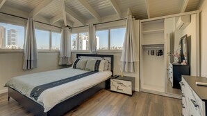 Ein modernes Schlafzimmer mit einem großen Bett, einem begehbaren Kleiderschrank und Blick auf die Stadt.