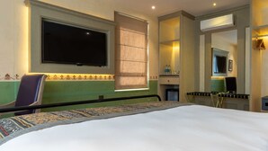 A hotel room with a large bed, a flat-screen TV mounted on the wall, a window with a blind, and a mirror above the bed. - Seto Ghar Hotel Pvt. Ltd. (Kathmandu)