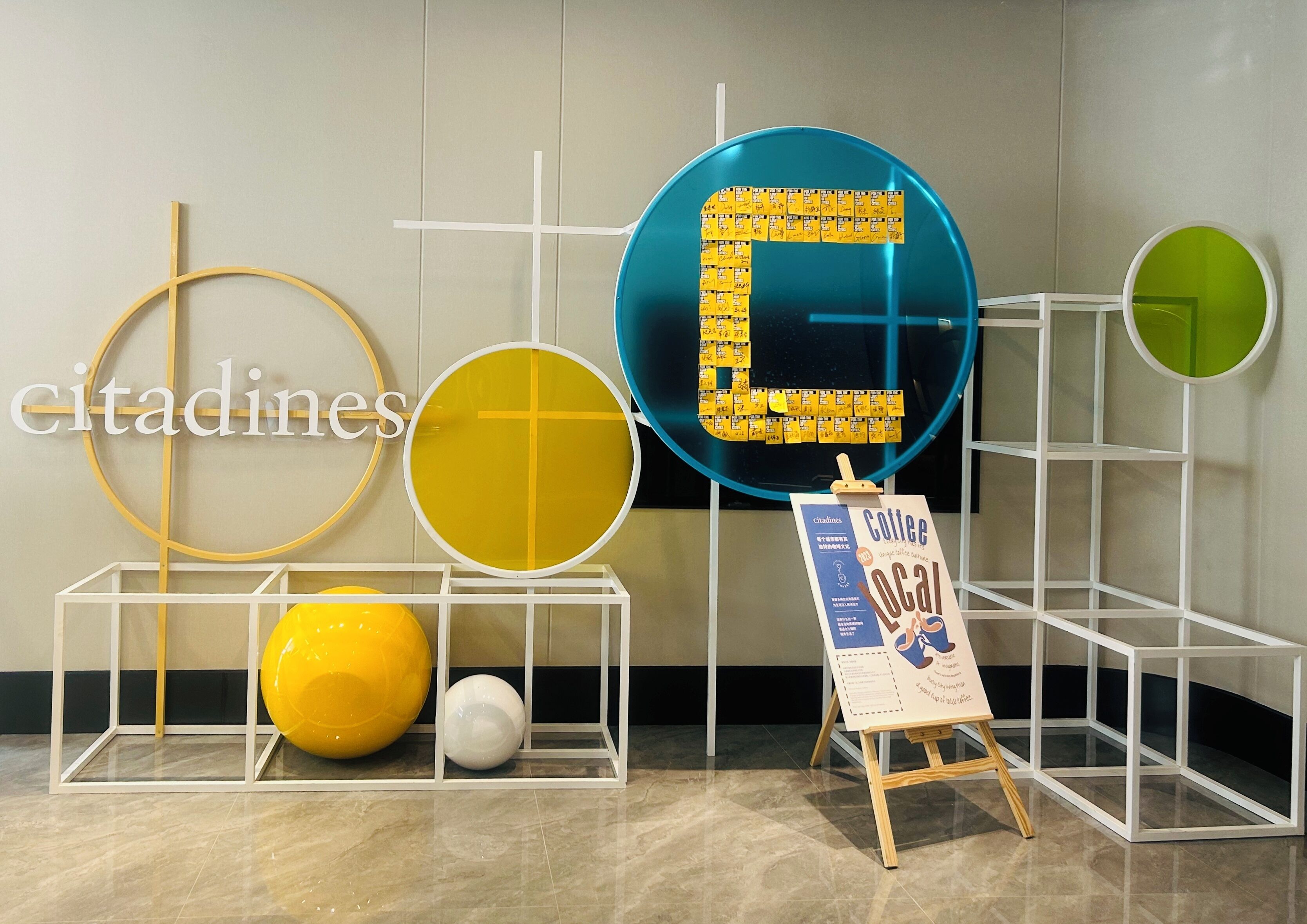 A modern interior with geometric wall decorations, a display stand with a sign, and a marble floor.