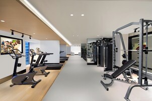 Uma academia com equipamentos de ginástica, incluindo esteiras e aparelhos de musculação.