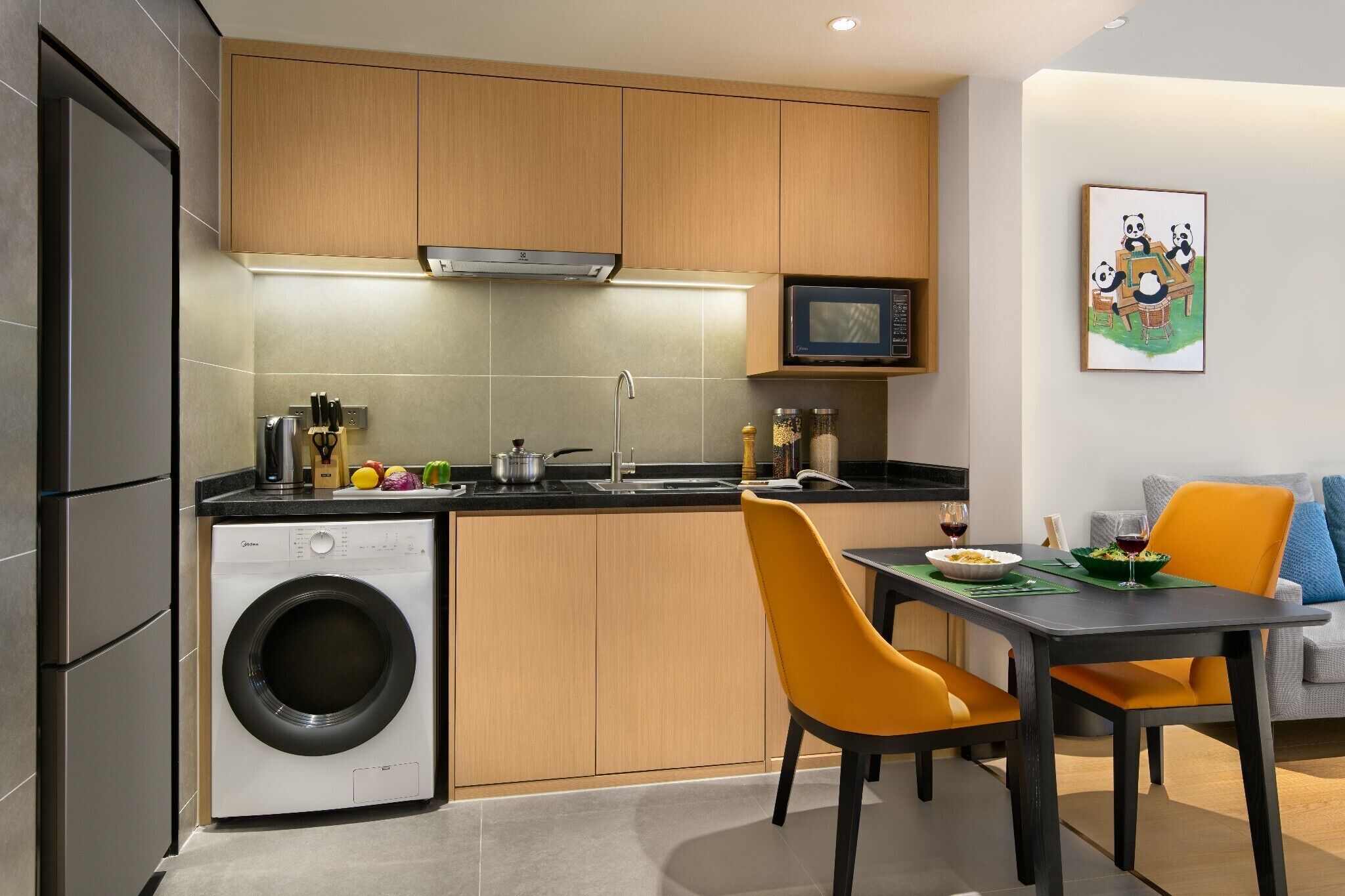 A compact kitchen with a washing machine, microwave, and dining area with a table and chairs.