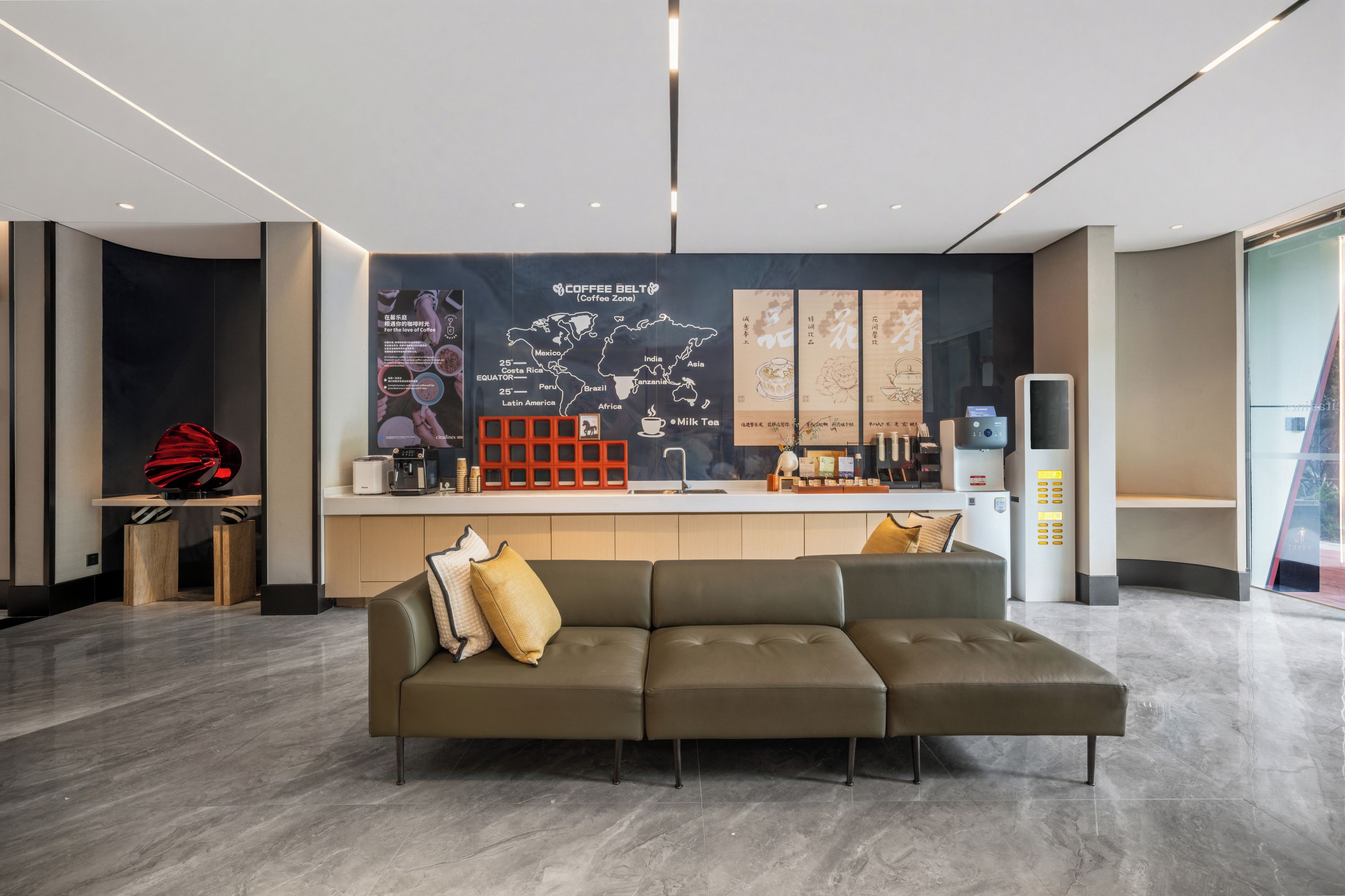 Uma área de recepção moderna com sofá, estação de café e parede exibindo um mapa-múndi e gráficos com tema de café.