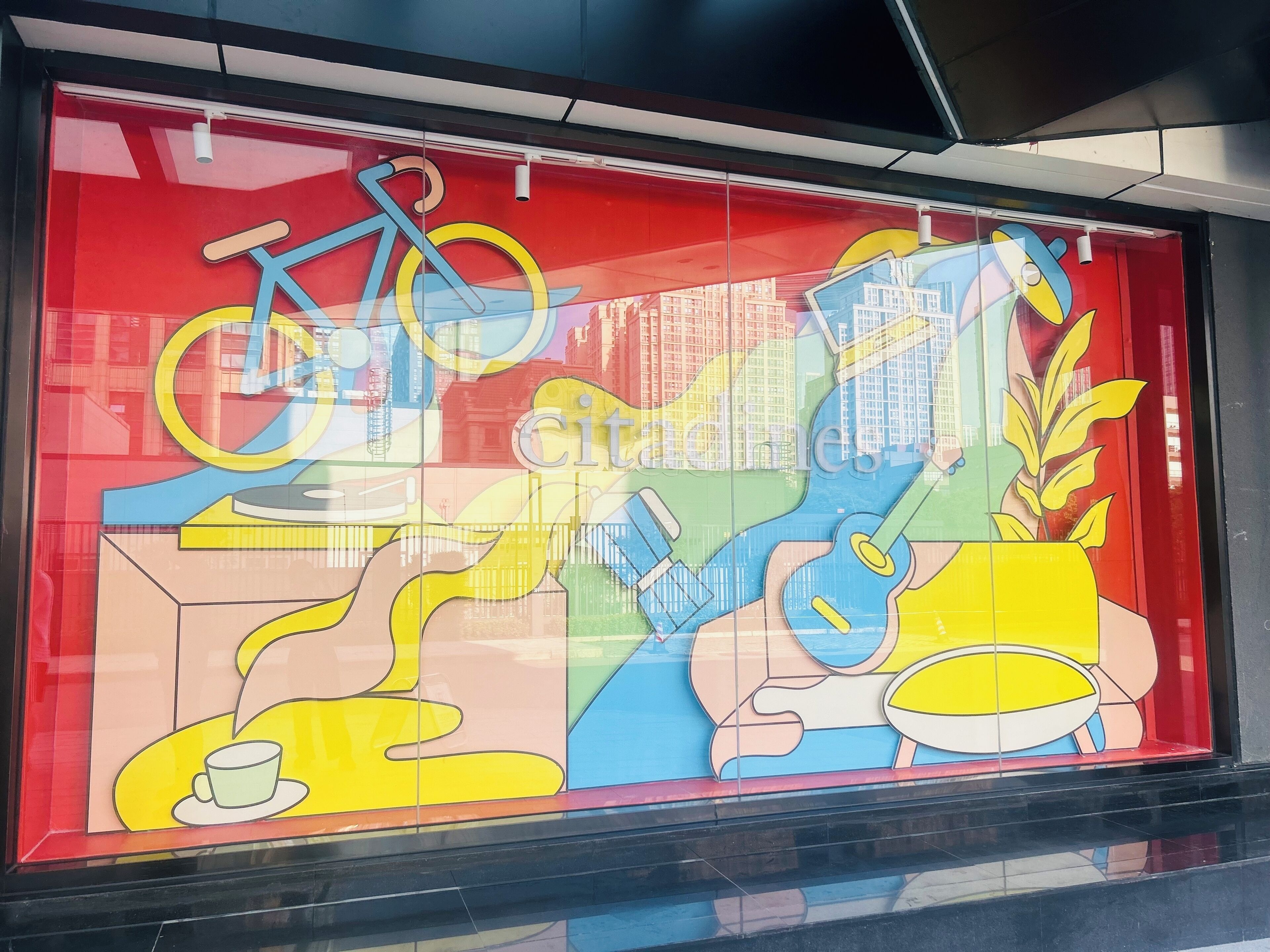 A colorful mural with a bicycle, a cup, and a plant.