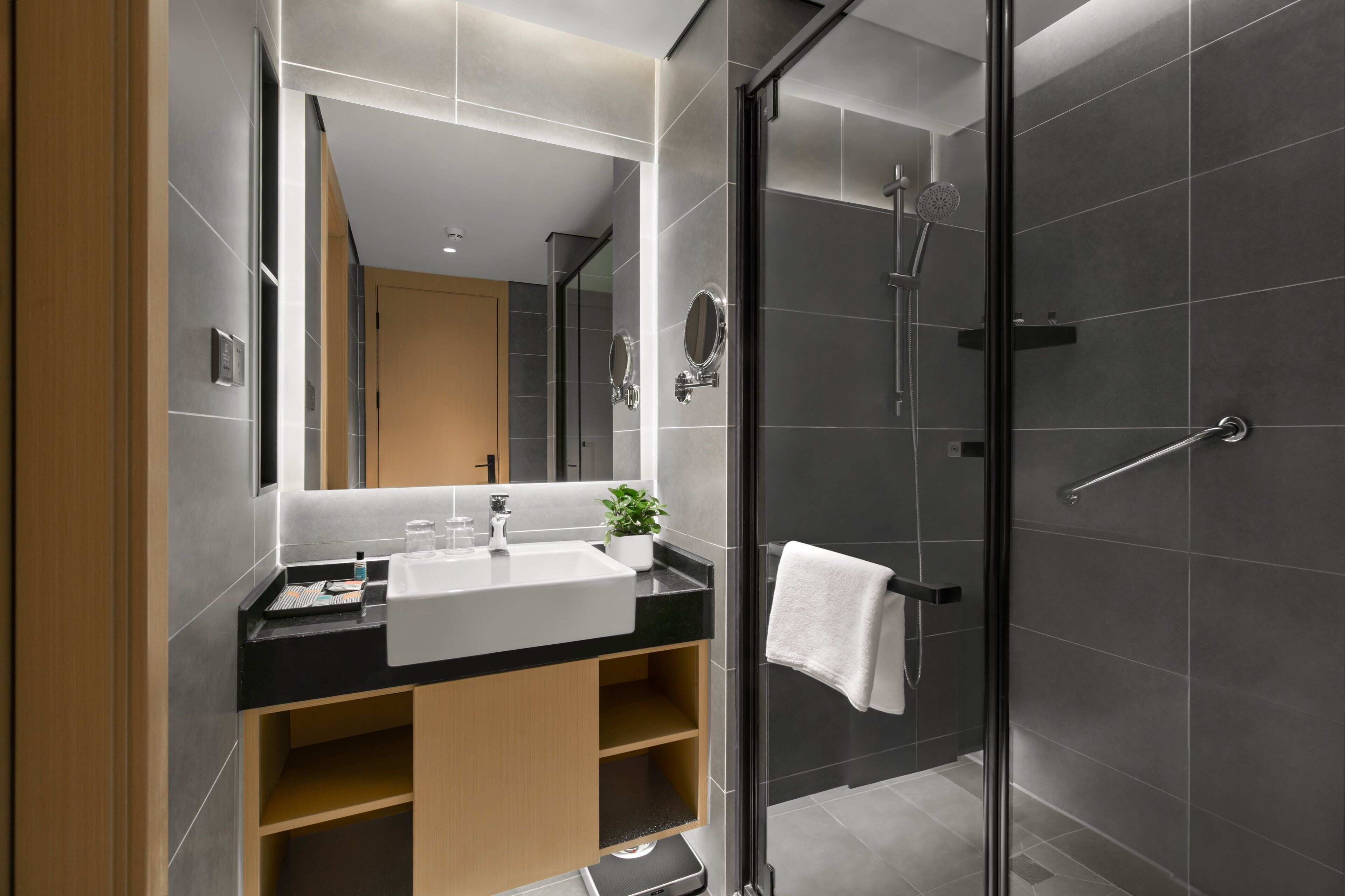 A modern bathroom with a large mirror, a sink, and a shower.