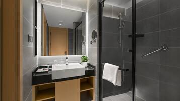 A modern bathroom with a large mirror, a sink, and a shower.