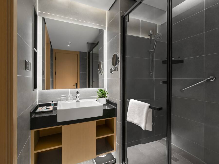 A modern bathroom with a large mirror, a sink, and a shower.