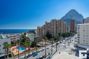 A coastal cityscape with high-rise buildings, a clear blue sky, and a mountain in the background. - Apolo XVI 2 6 29 - Grupo Turis - Calpe, Costa Blanca (Calpe)