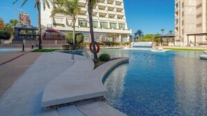 Une piscine à bord incurvé, une bouée de sauvetage et un palmier.
