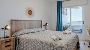 Une chambre à coucher avec un lit, des lampes de chevet, une table de nuit en bois, un élément de décoration murale et une vue sur l’extérieur.