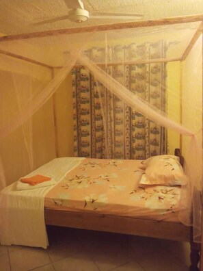 A single bed with a canopy, a bedside table, and curtains with a vehicle pattern.